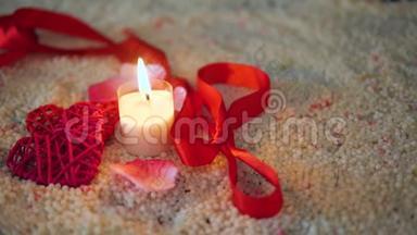 情人节的装饰画、丝带和蜡烛在沙子上燃烧